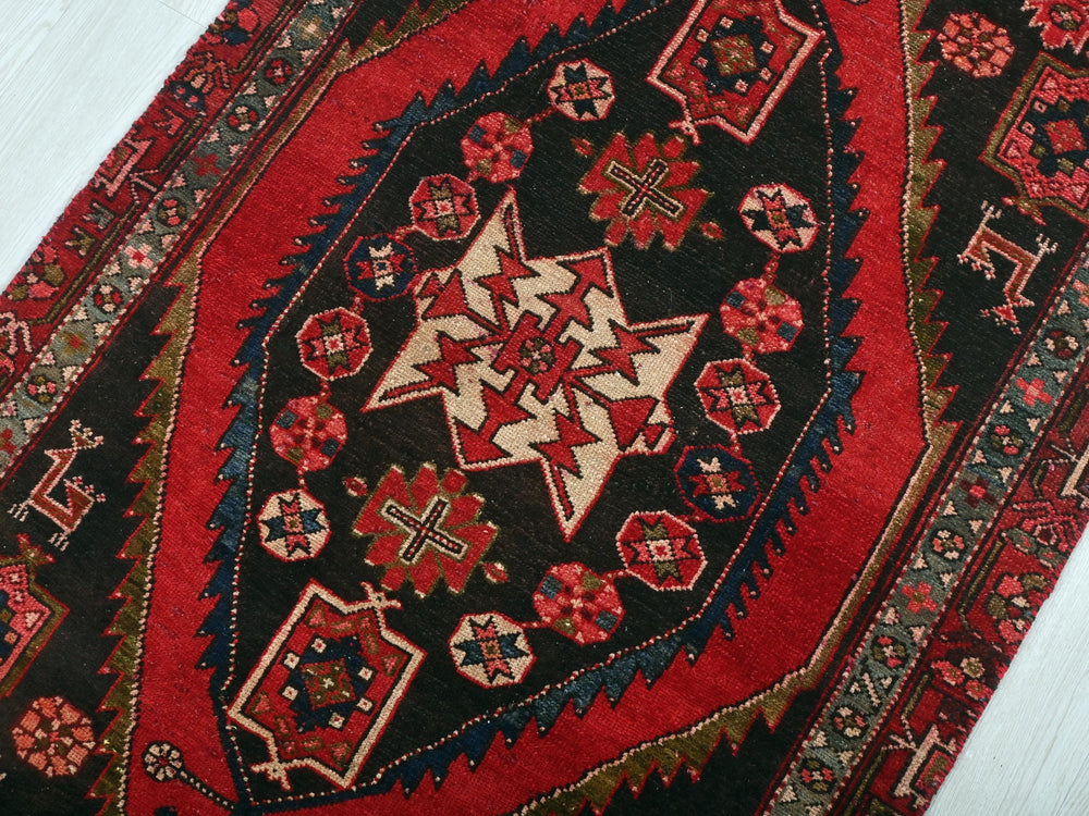 a red and black oriental rug on a white floor