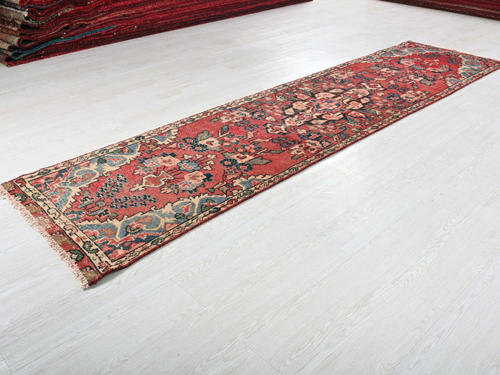 a red rug laying on the floor next to a pile of rugs