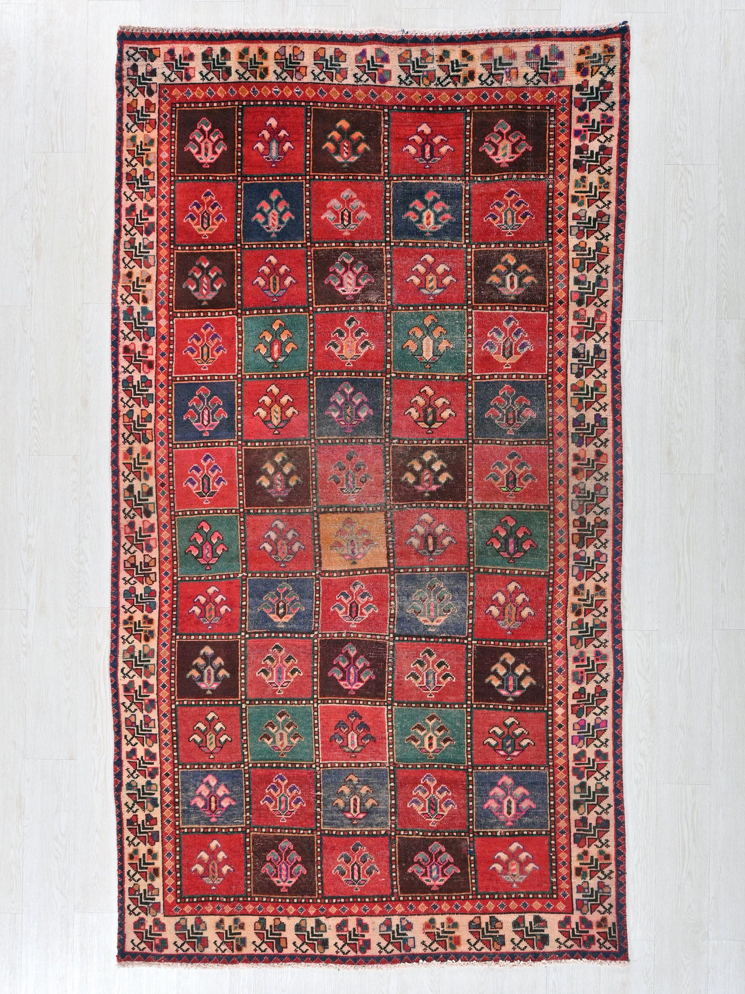 a red, blue, green, and brown rug on a white wall