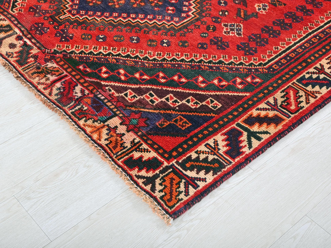 a red oriental rug on a white wooden floor