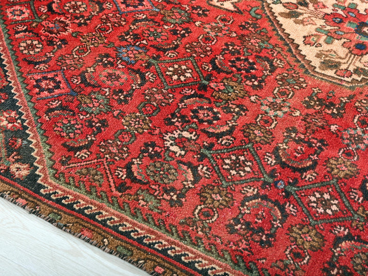 a red oriental rug on a white wooden floor