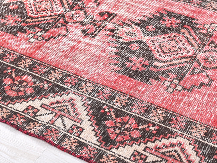 a red and black oriental rug on a wooden floor