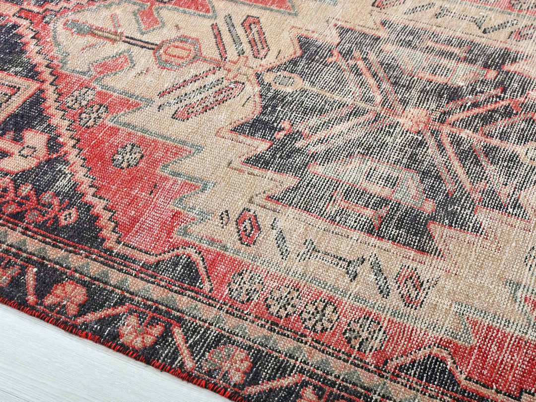a red and black oriental rug on a wooden floor