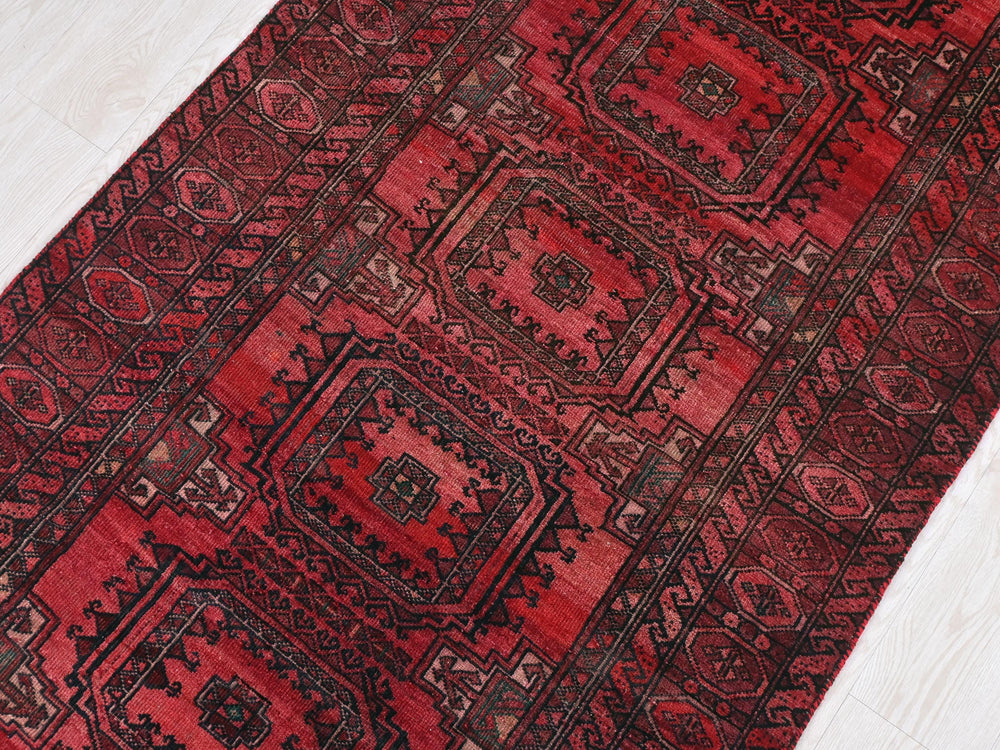 a red oriental rug on a white wooden floor