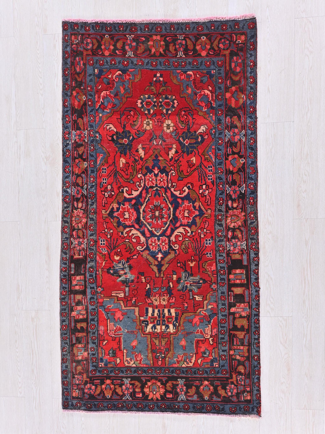 a red and blue oriental rug on a wooden floor