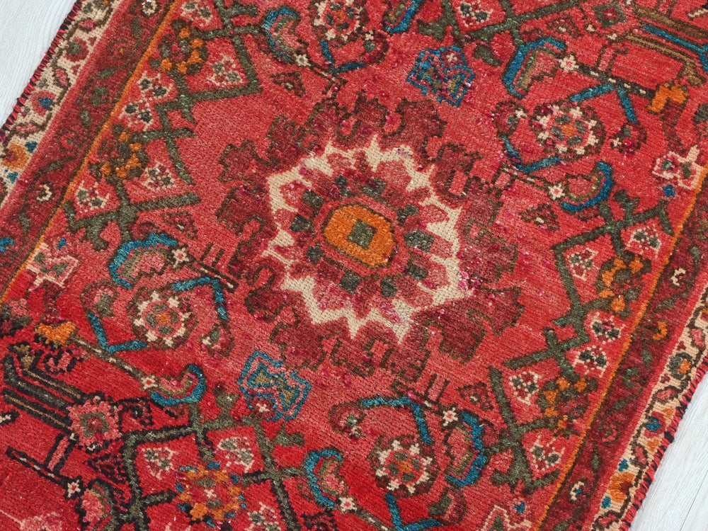 a red oriental rug on a white wooden floor