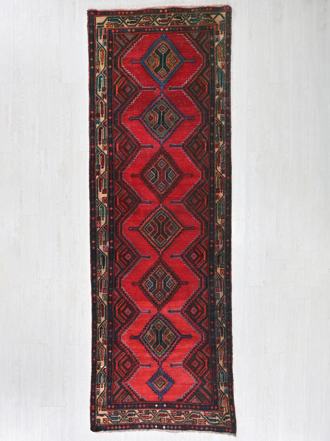 a red rug hanging on a white wall
