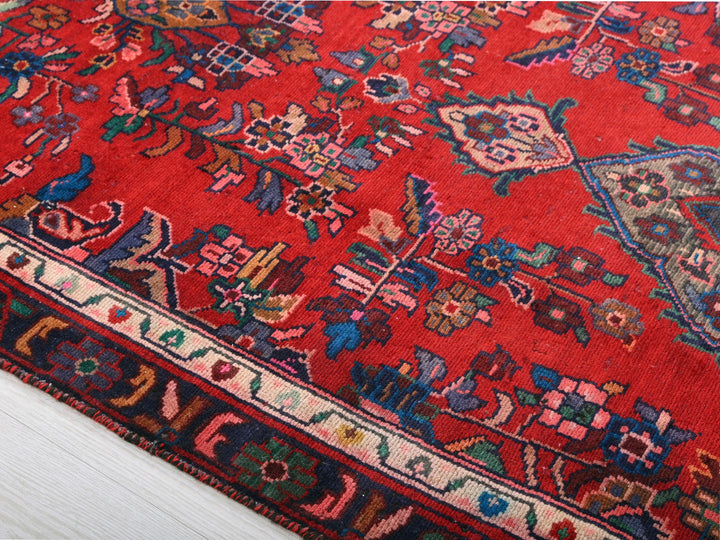 a red oriental rug on a white wooden floor