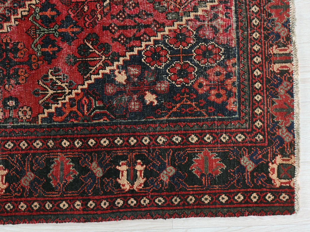 a red and black oriental rug on a white surface