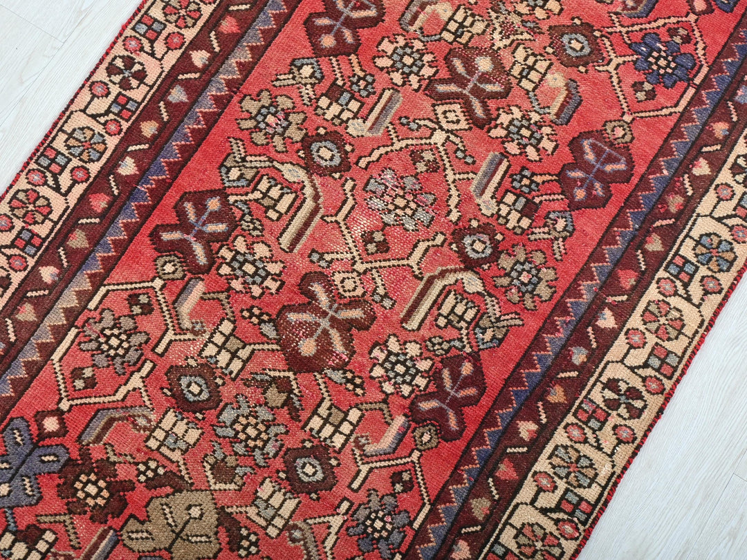 a red oriental rug on a white wooden floor