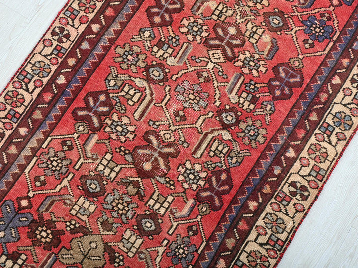 a red oriental rug on a white wooden floor