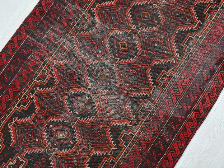 a red and black oriental rug on a white floor