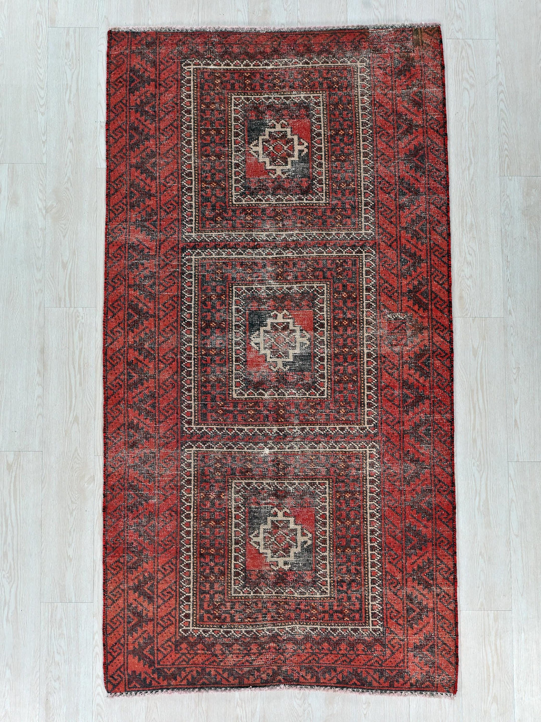 a red and black rug on a white floor