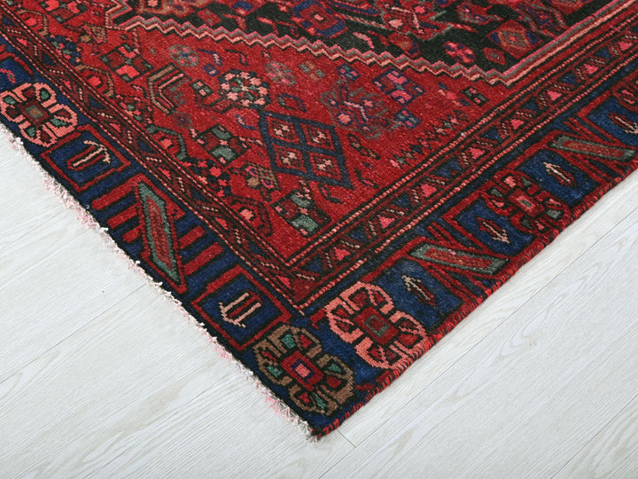 a red oriental rug on a white wooden floor