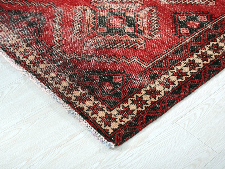 a red and black oriental rug on a white floor