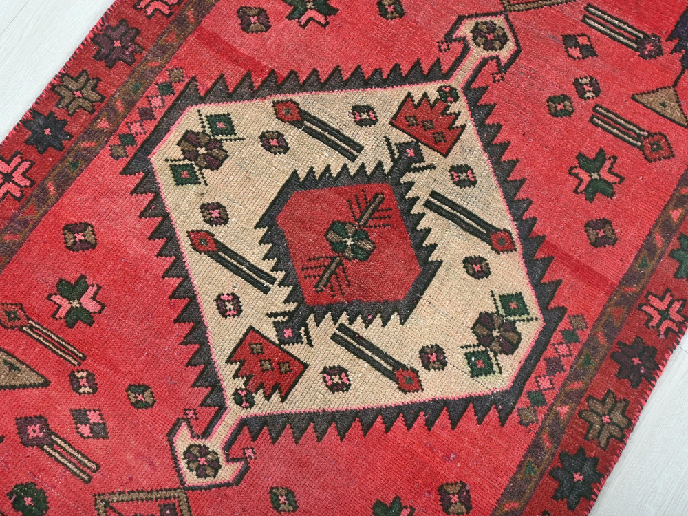 a red rug with a design on the middle of it