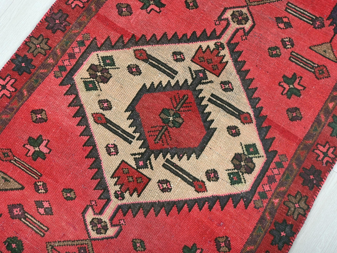 a red rug with a design on the middle of it