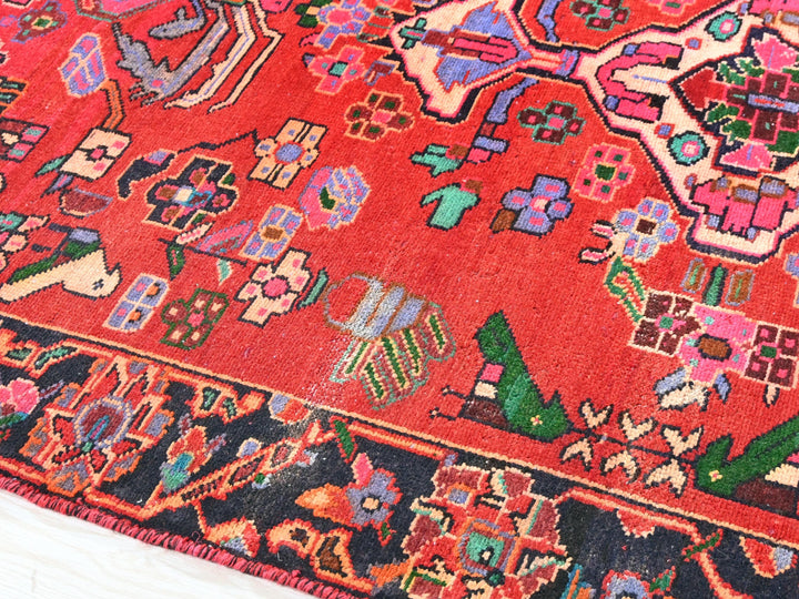 a red oriental rug with a colorful design