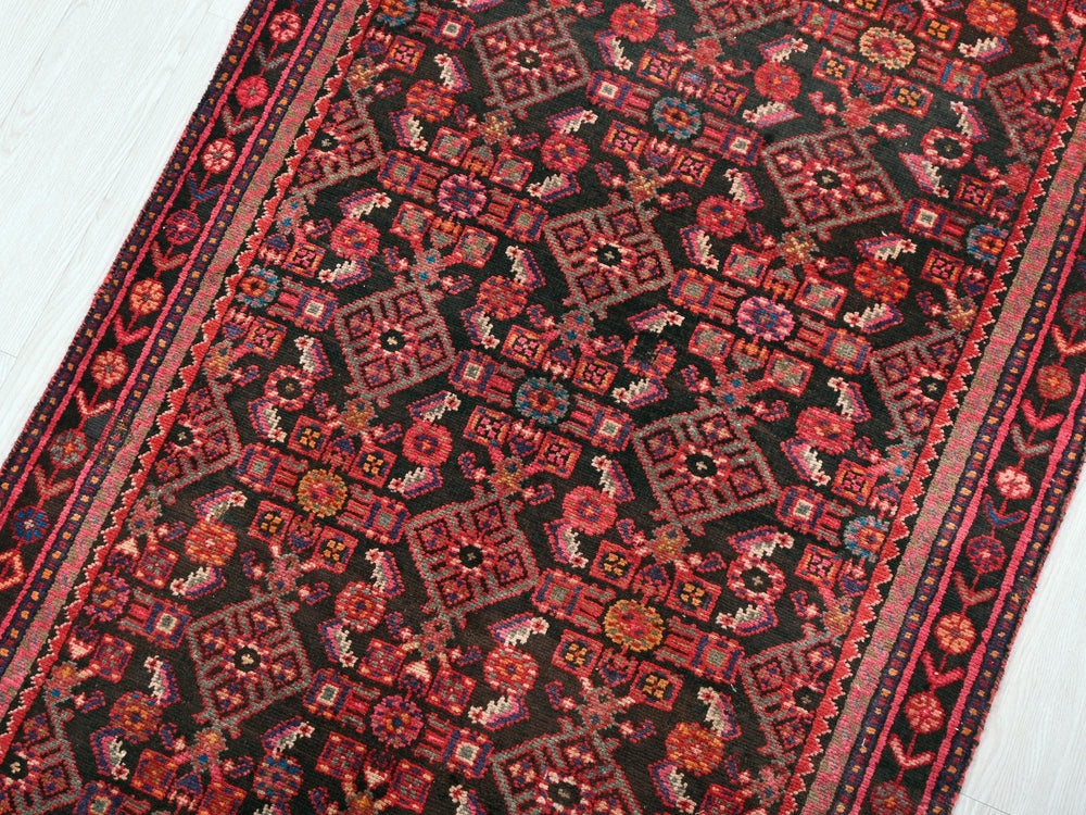 a red and black oriental rug on a white floor
