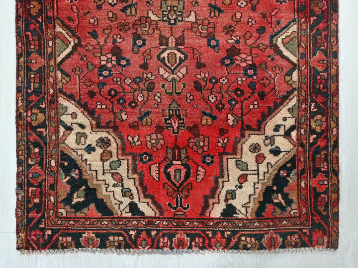 a red rug with a black border on a white wall