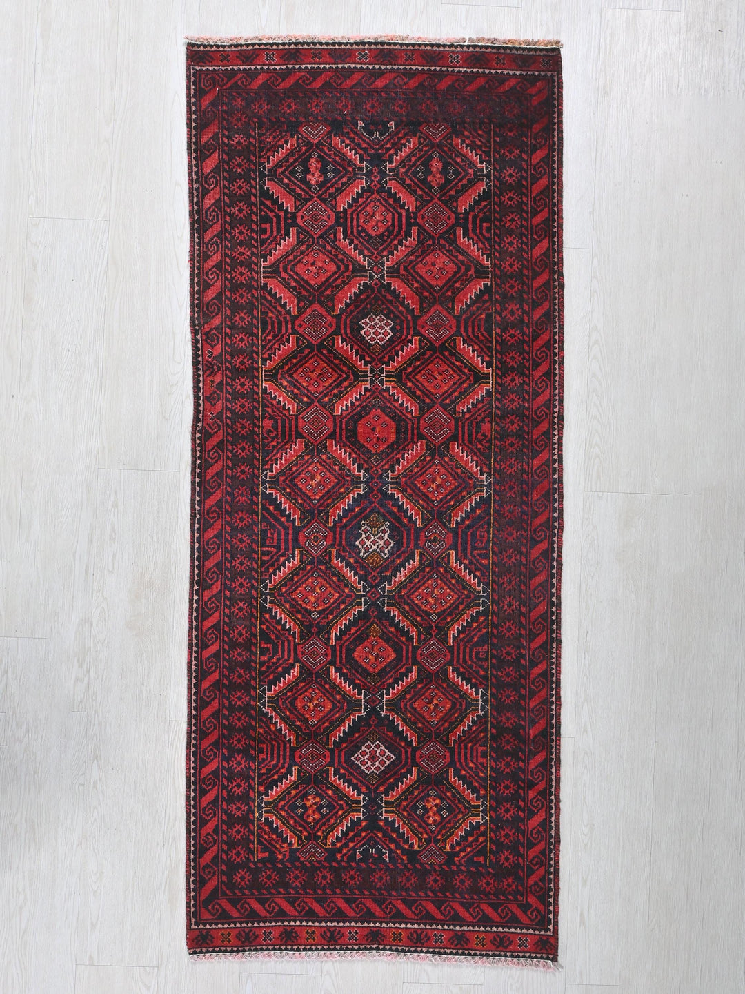 a red rug hanging on a white wall