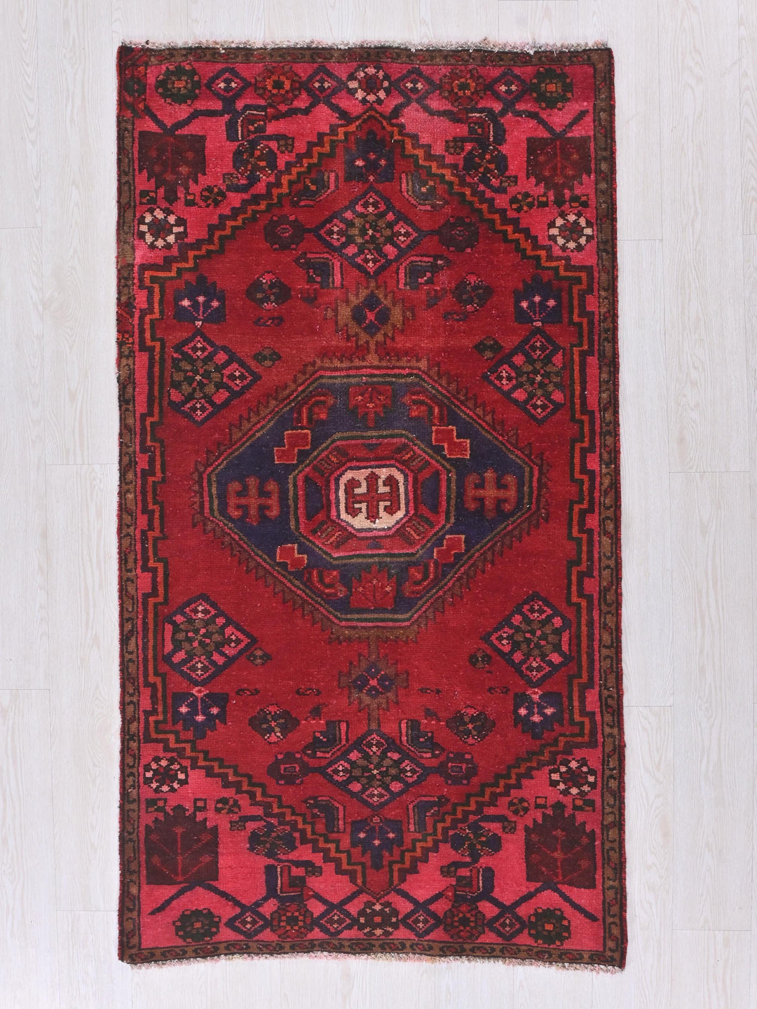a red rug with a design on the middle of it