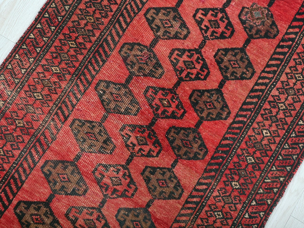 a red and black oriental rug on a white floor