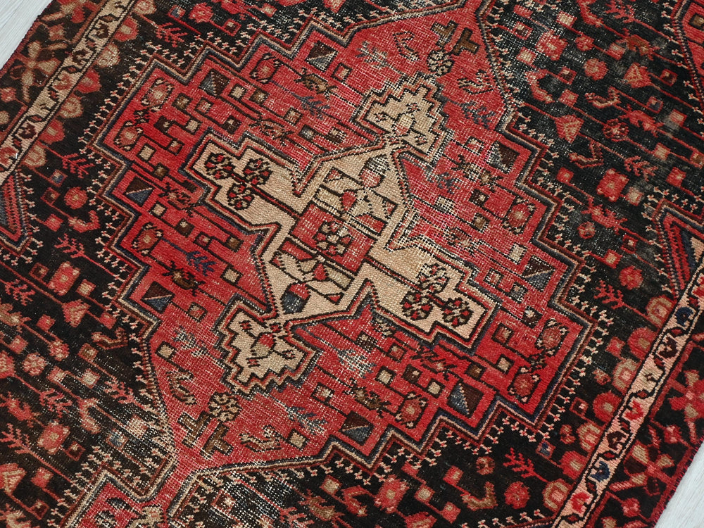 a red and black oriental rug on a white floor