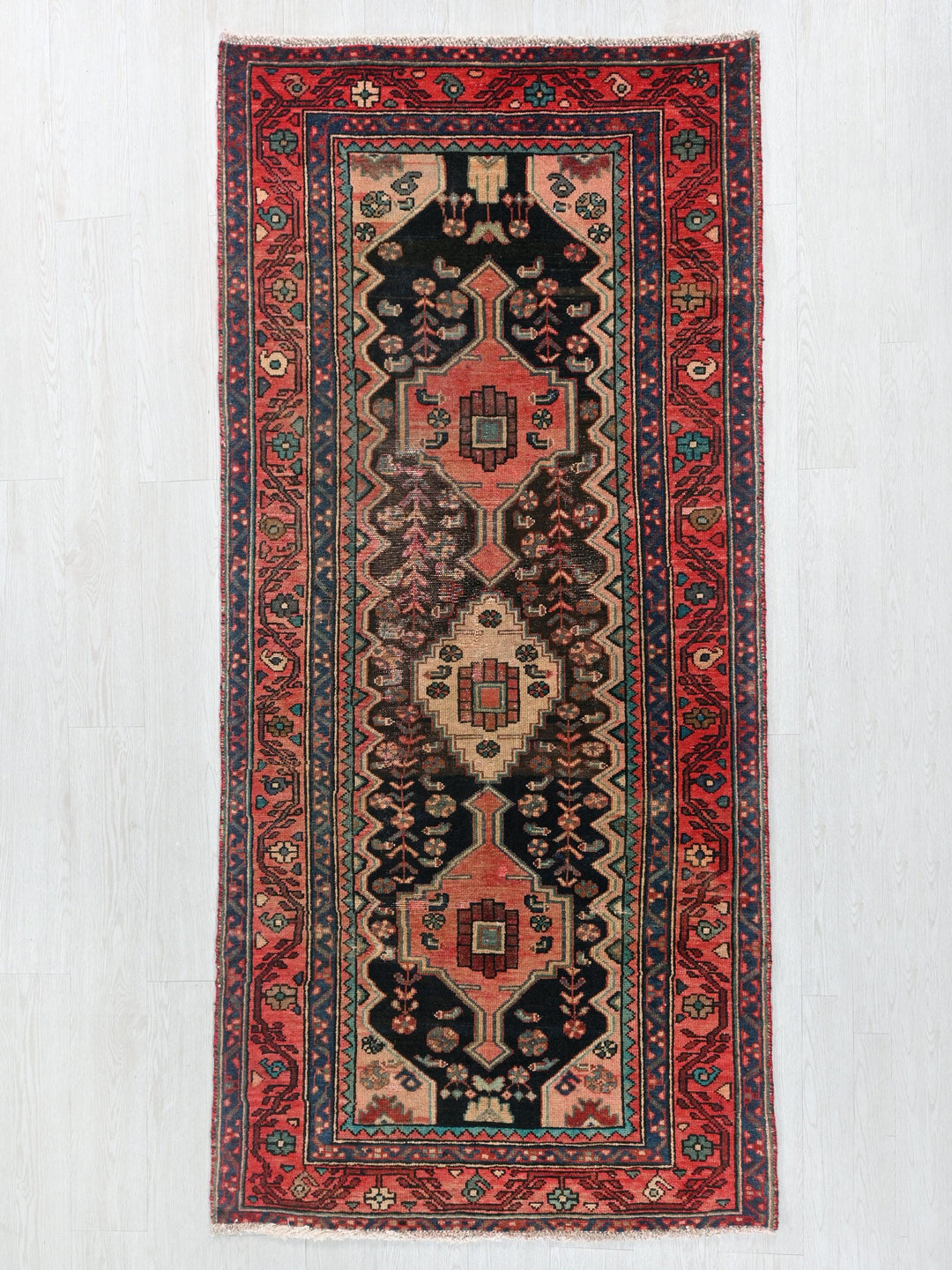 a red and black rug hanging on a wall