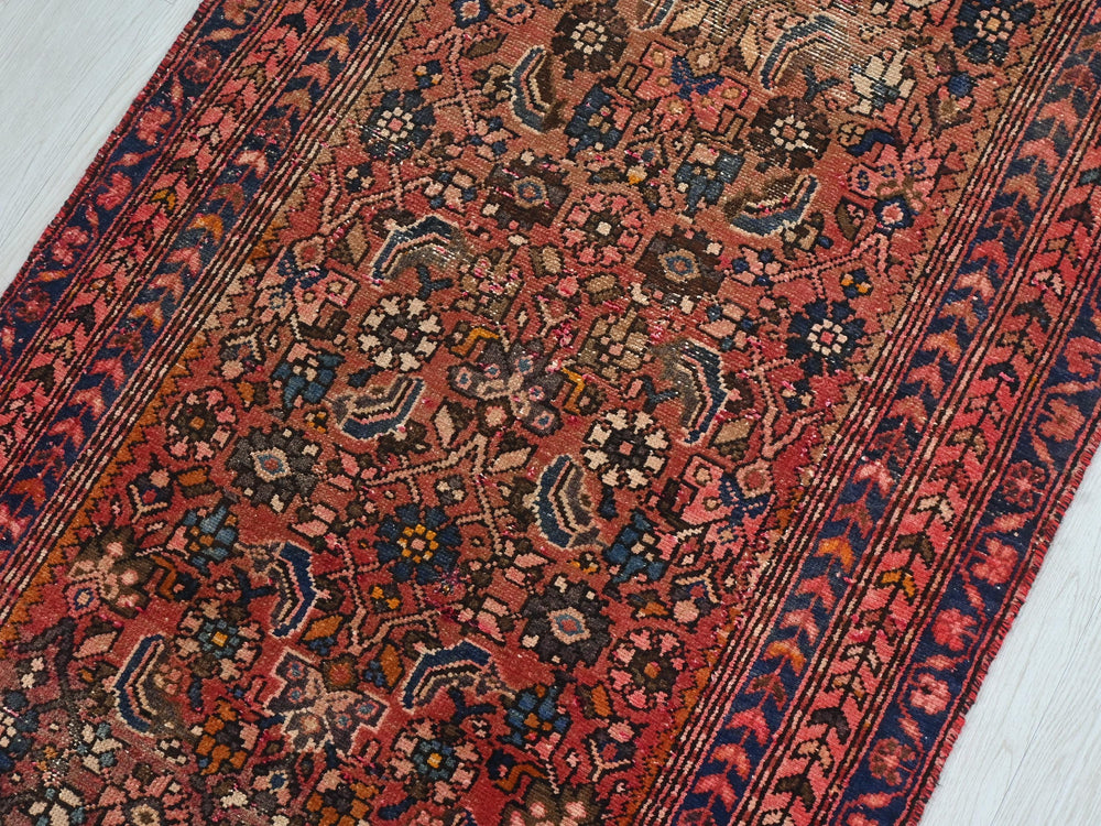 a red rug with a blue border on a white floor