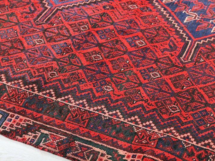 a red and blue rug on a wooden floor
