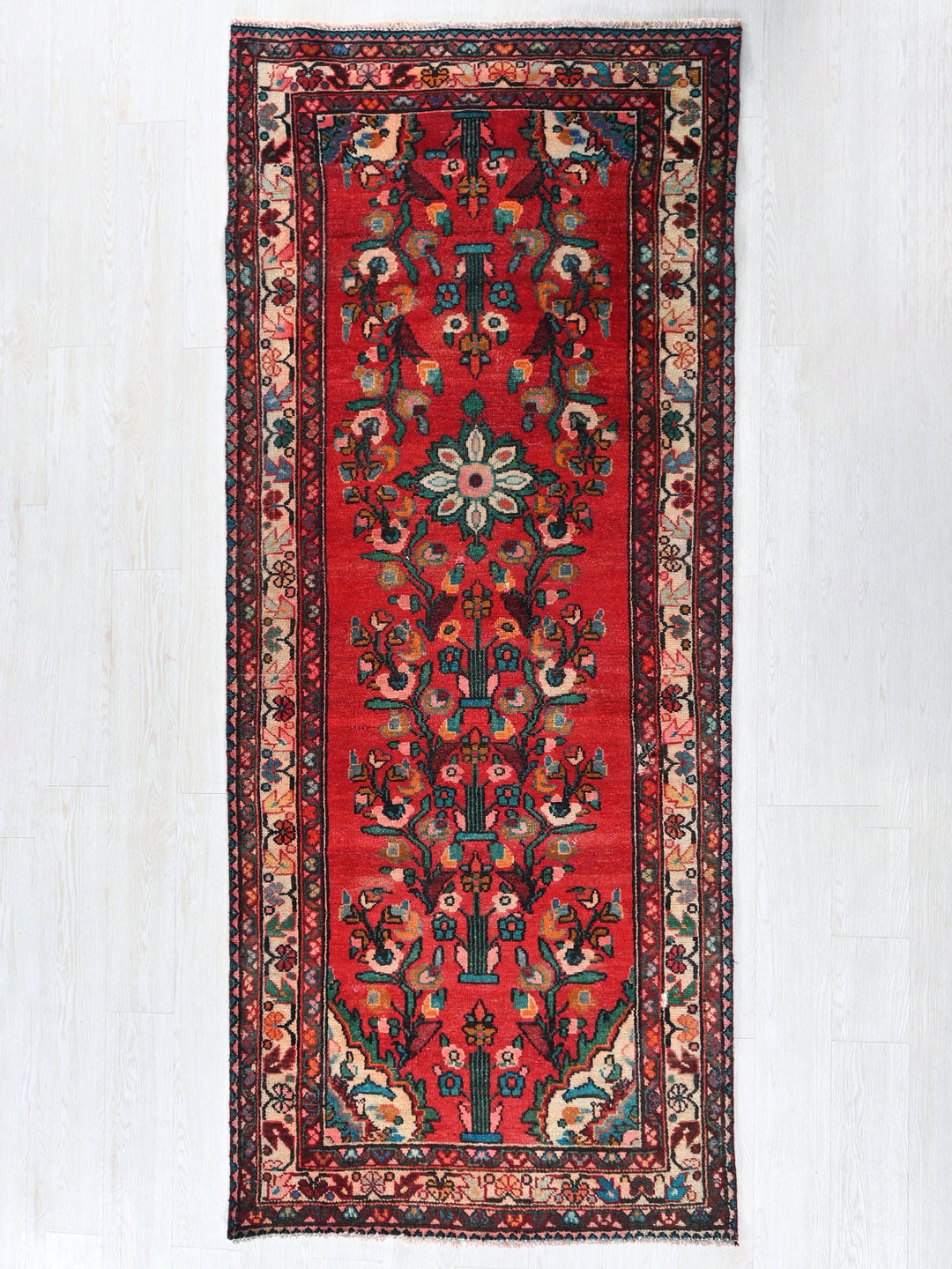 a red rug hanging on a white wall