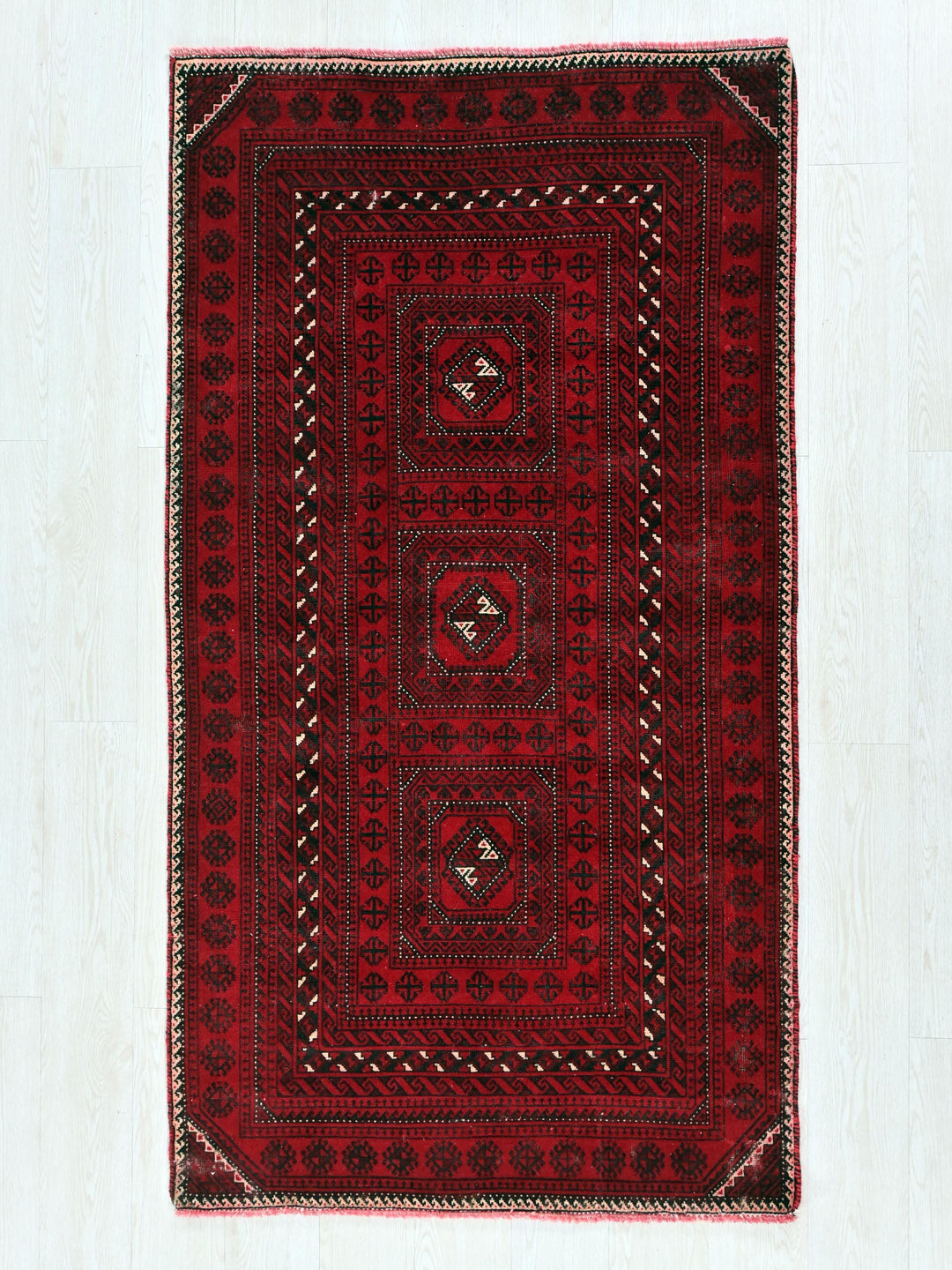 a red and black rug on a white floor