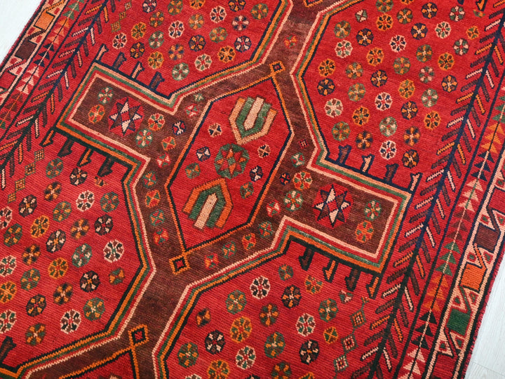 a red oriental rug with a geometric design