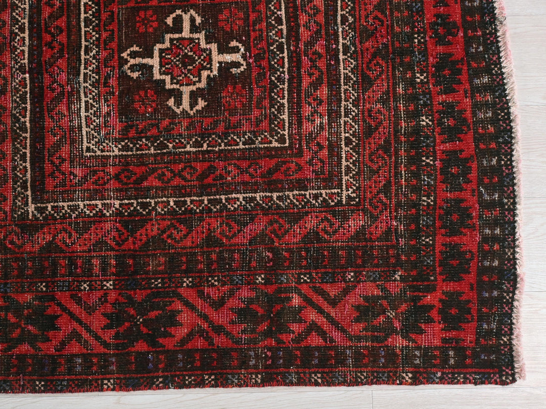 a red and black rug on a white floor