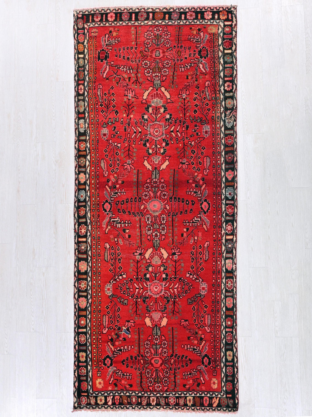 a red rug hanging on a white wall