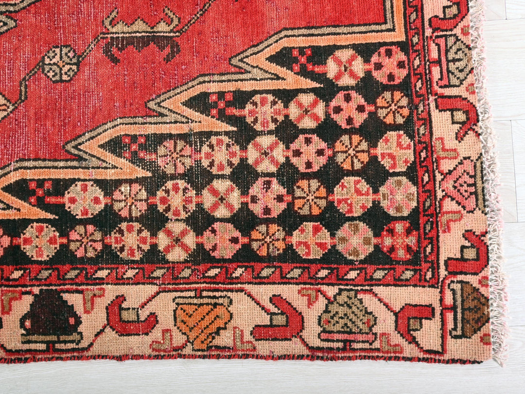 a red and black oriental rug on a wooden floor