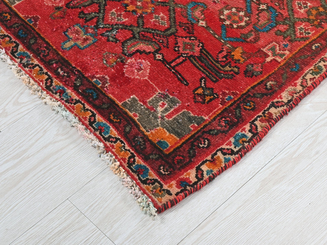 a red oriental rug on a white wooden floor