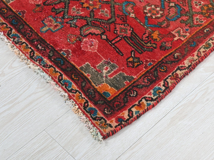 a red oriental rug on a white wooden floor
