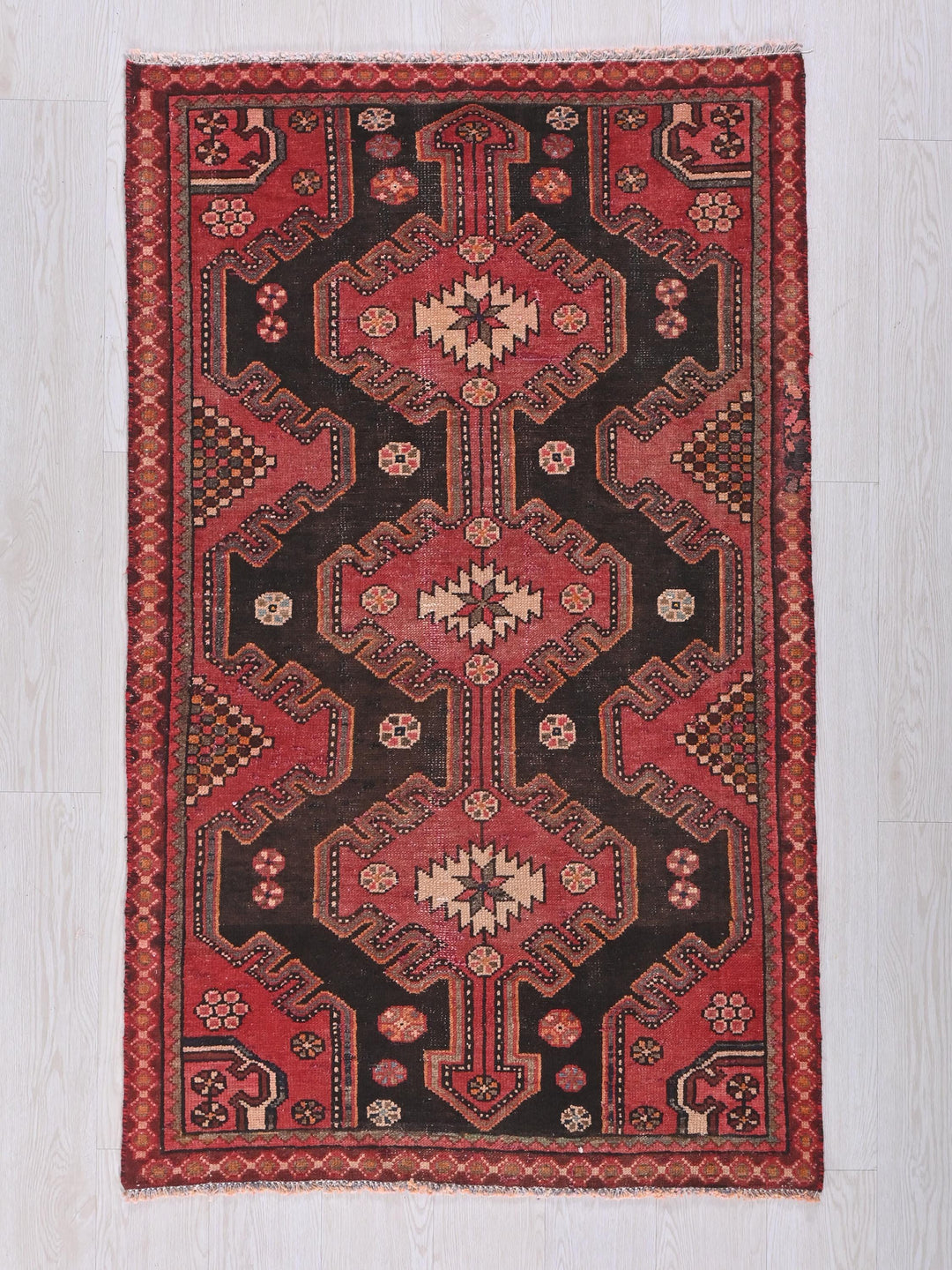 a red and black rug on a white floor