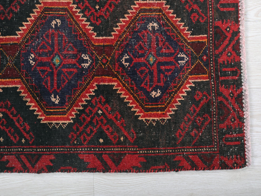 a red and black oriental rug on a white surface