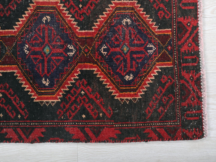 a red and black oriental rug on a white surface