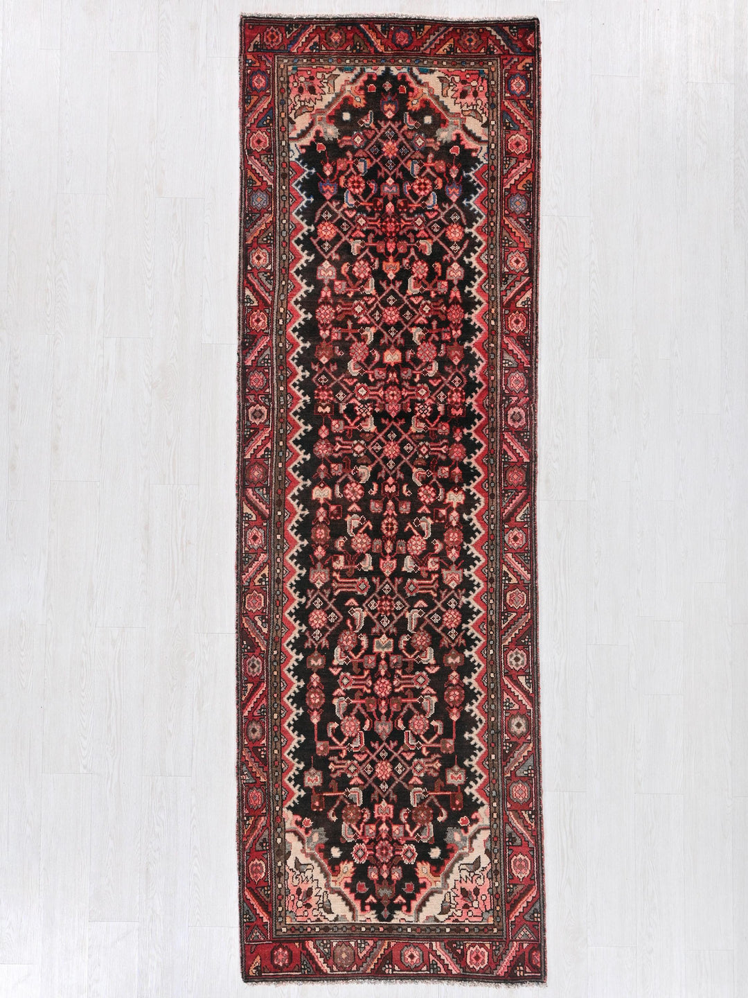 a red and black rug hanging on a wall