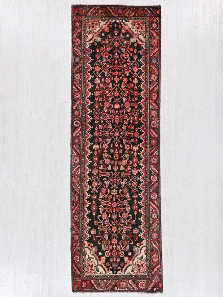 a red and black rug hanging on a wall