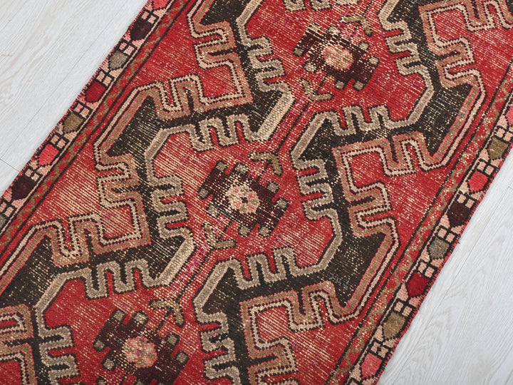 a red and black oriental rug on a white wooden floor