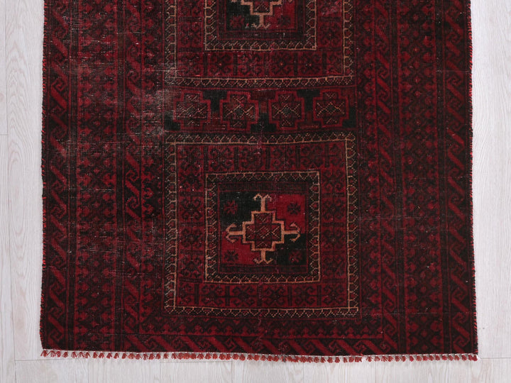 a red and black rug on a wooden floor