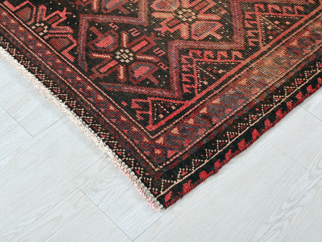 a red and black oriental rug on a white floor