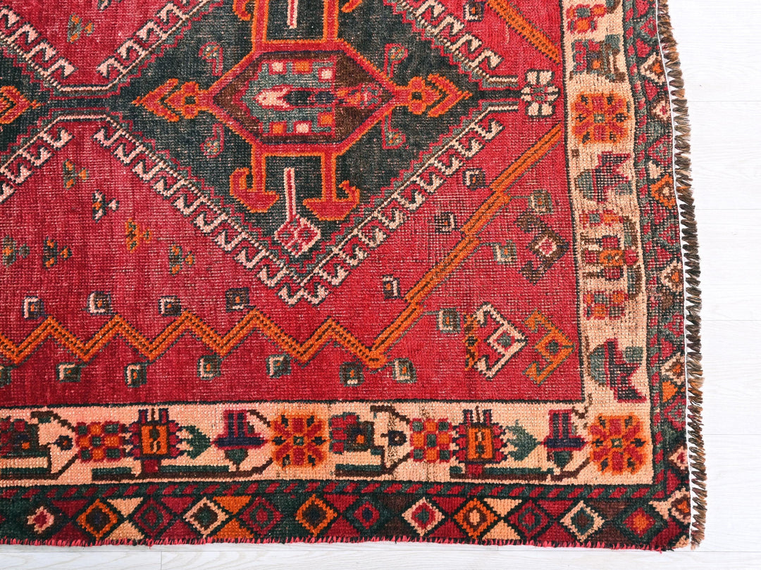 a red rug with a design on the middle of it