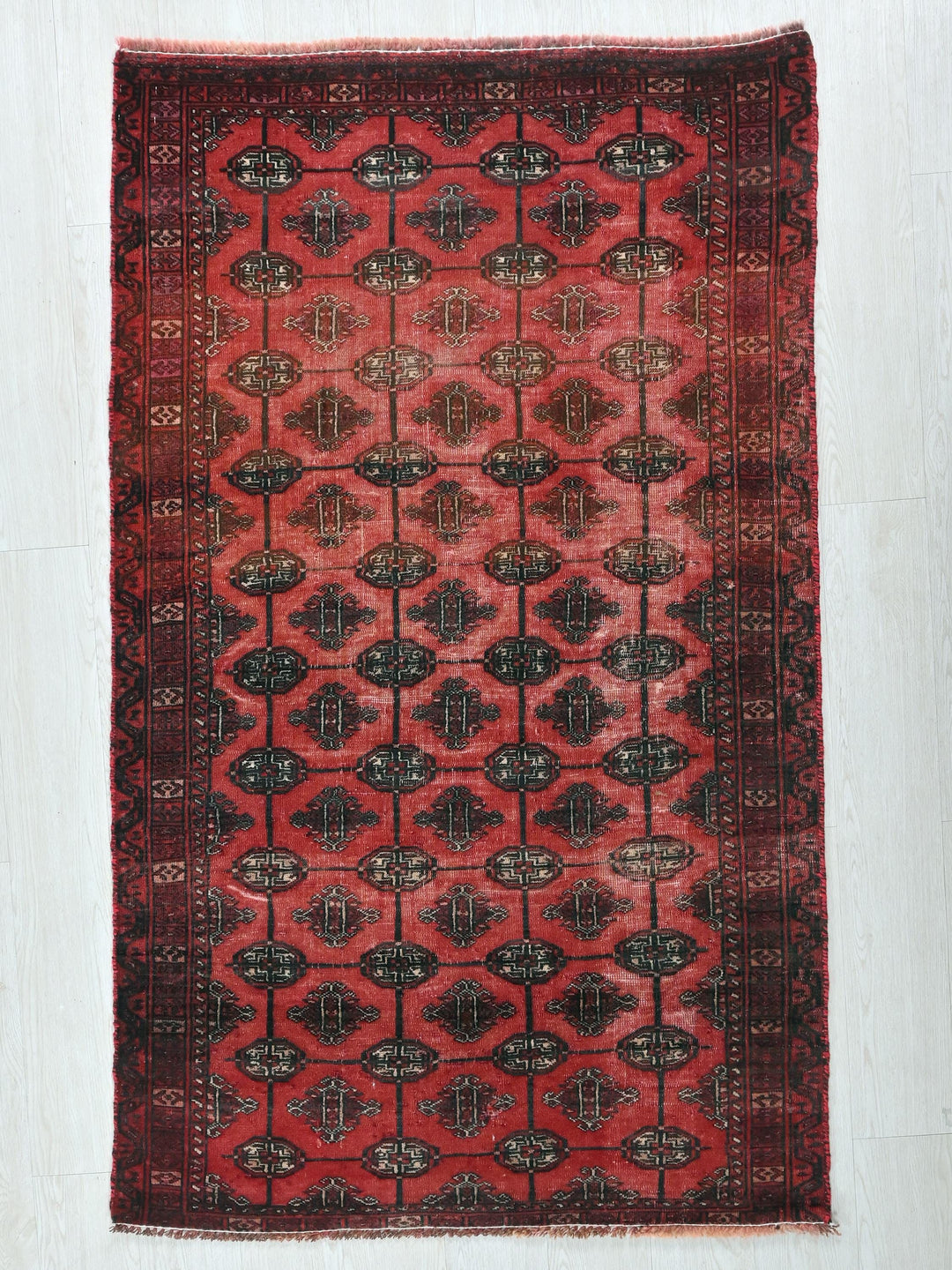 a red and black rug on a white floor