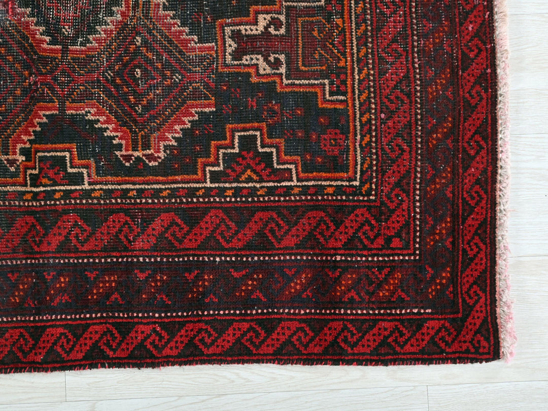 a red and black rug on a white floor